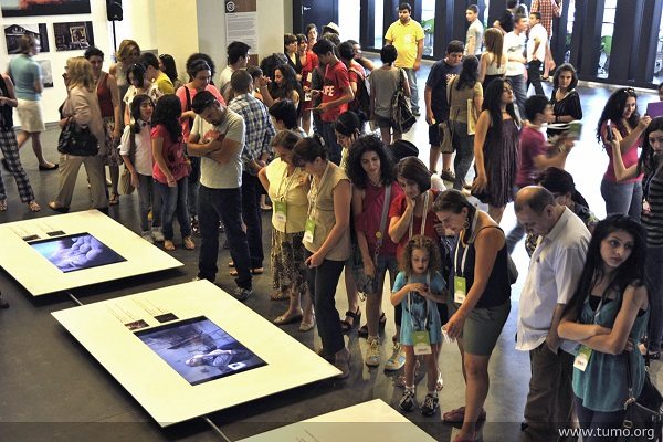Attendees view a series of photo stories during the opening of an exhibition of over 40 photojournalism students.