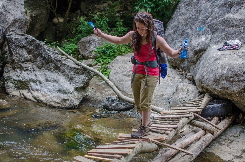Lexee Andonian carefully crosses a bridge near Shushi. Brush in hand, she's ready to paint the next blue marking.